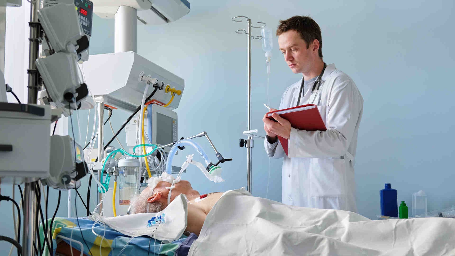 Doctor rounding in the ICU at a patient's bedside